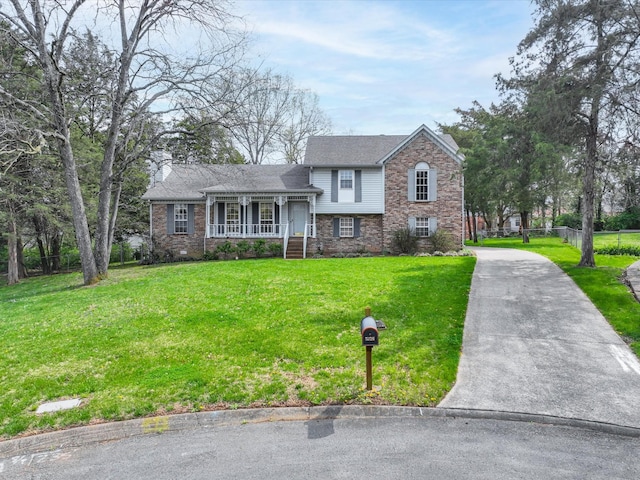 tri-level home featuring concrete driveway, a front lawn, a porch, brick siding, and fence