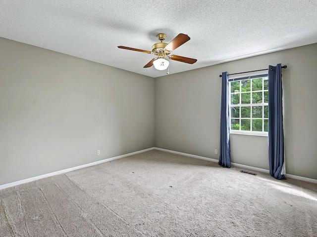 carpeted empty room featuring a textured ceiling, baseboards, a ceiling fan, and visible vents