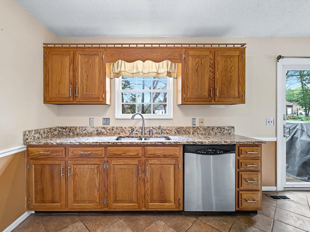 kitchen featuring brown cabinetry, dishwasher, a sink, and plenty of natural light