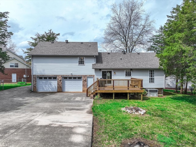 back of property featuring roof with shingles, driveway, an attached garage, central AC unit, and a lawn