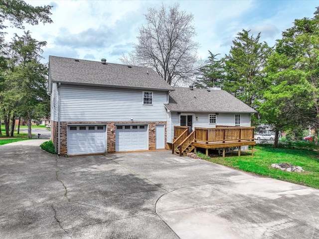 back of property with an attached garage, a shingled roof, a lawn, and driveway