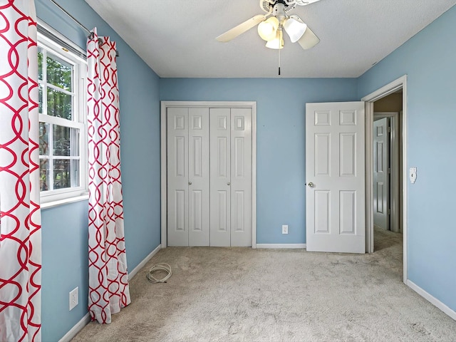 unfurnished bedroom featuring carpet, a closet, baseboards, and a ceiling fan