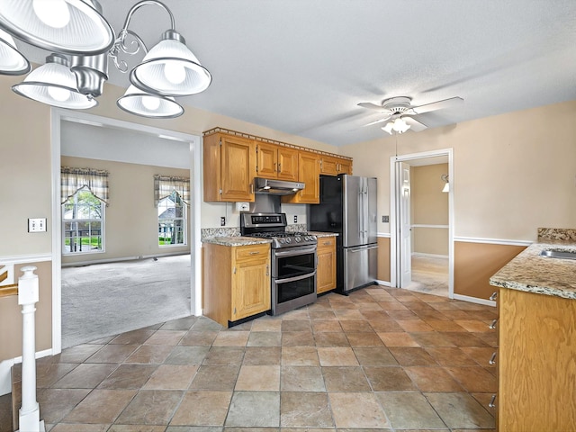 kitchen with light stone counters, ceiling fan, under cabinet range hood, stainless steel appliances, and light carpet