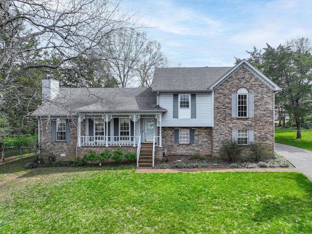 tri-level home featuring a chimney, a front yard, brick siding, a porch, and a shingled roof