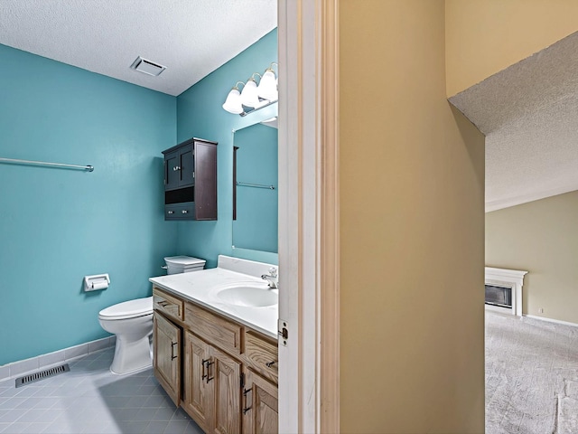 bathroom featuring toilet, a textured ceiling, vanity, and visible vents