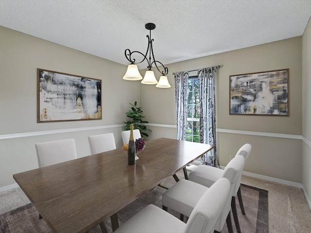 dining room with a textured ceiling, baseboards, and carpet