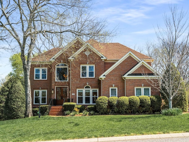 colonial-style house featuring a front yard and brick siding