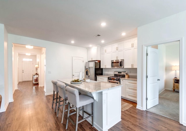 627 Prominence Rd, Columbia, TN 38401 - kitchen featuring appliances with stainless steel finishes, a center island with sink, a breakfast bar, dark wood-style floors, and recessed lighting