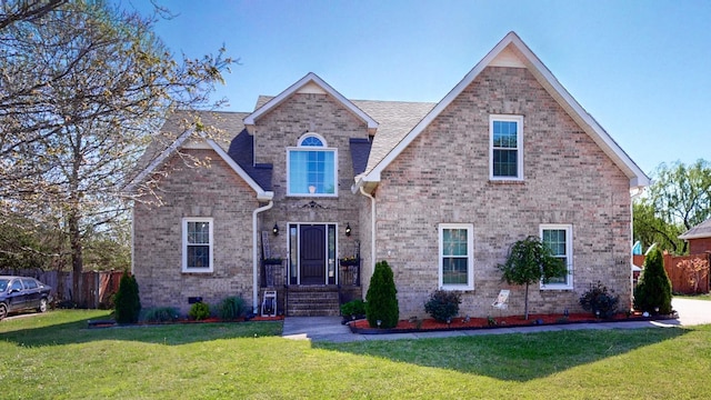 view of front of home featuring brick siding, a front yard, and fence