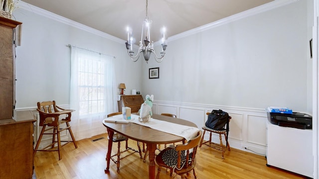 dining room with ornamental molding, a notable chandelier, visible vents, and light wood finished floors