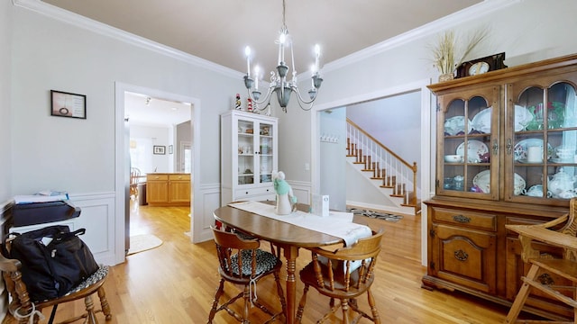dining area featuring light wood-style floors, stairs, ornamental molding, and an inviting chandelier