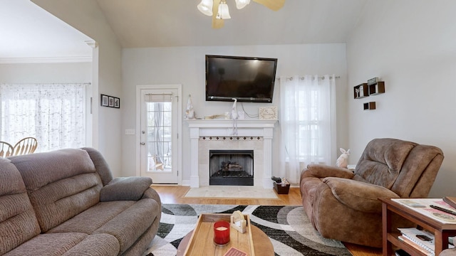 living area featuring lofted ceiling, a ceiling fan, wood finished floors, and a tiled fireplace