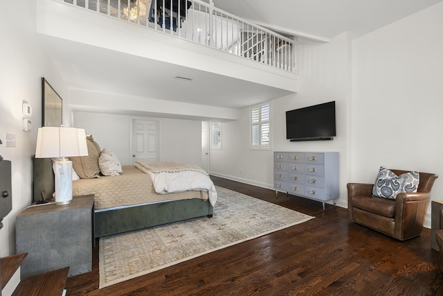 bedroom featuring wood finished floors, baseboards, and a towering ceiling
