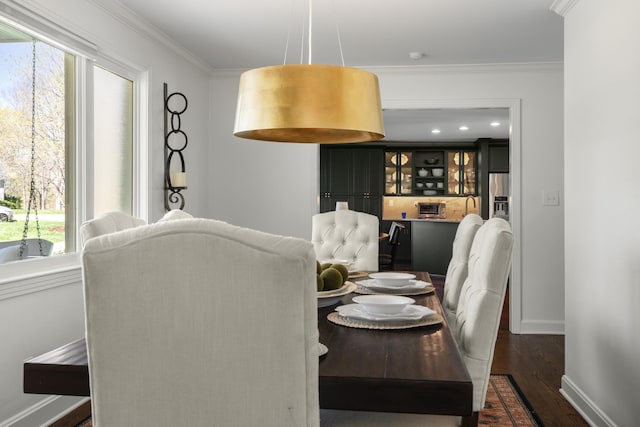 dining space featuring baseboards, ornamental molding, and dark wood finished floors