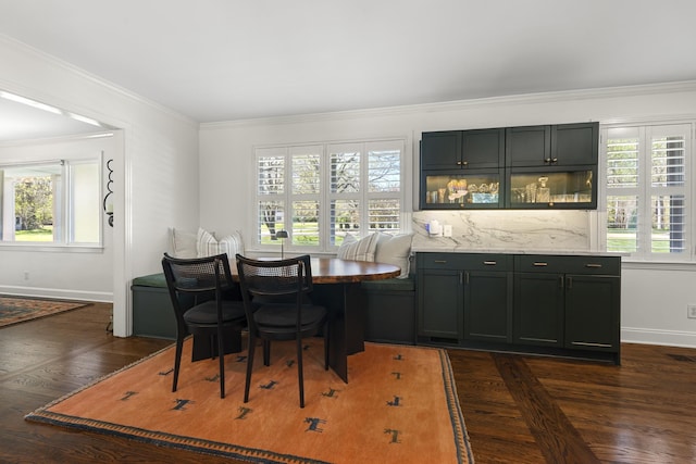 dining space with a wealth of natural light, dark wood-type flooring, baseboards, and ornamental molding