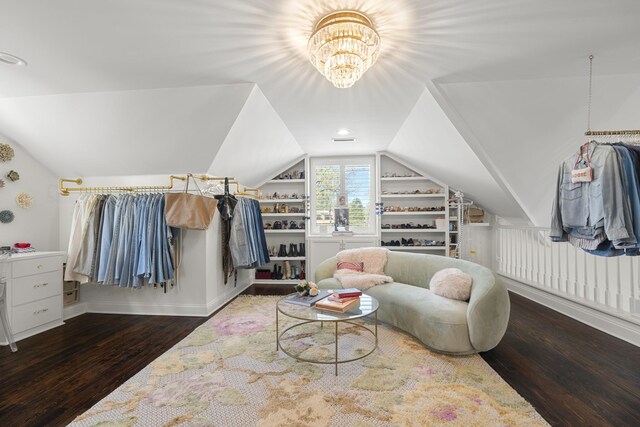 living area featuring wood finished floors, a notable chandelier, built in shelves, and vaulted ceiling