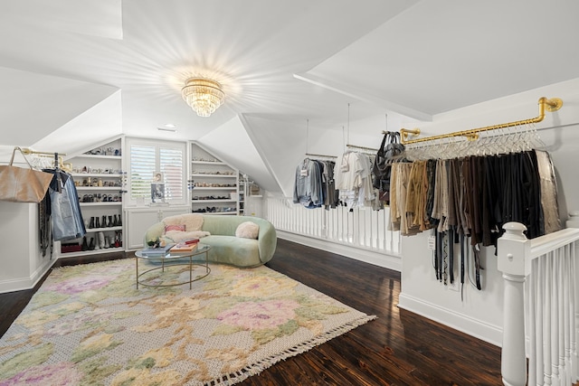 interior space featuring wood finished floors, baseboards, built in shelves, and vaulted ceiling
