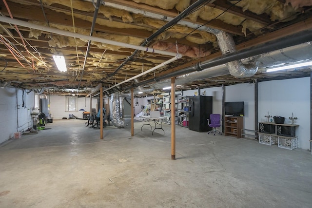 unfinished below grade area featuring gas water heater and black fridge with ice dispenser