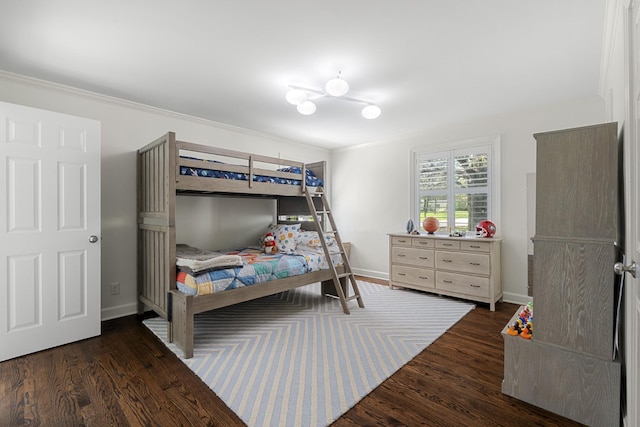 bedroom with wood finished floors, baseboards, and ornamental molding