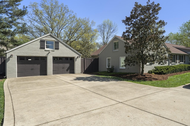 view of side of home with brick siding, a detached garage, and fence