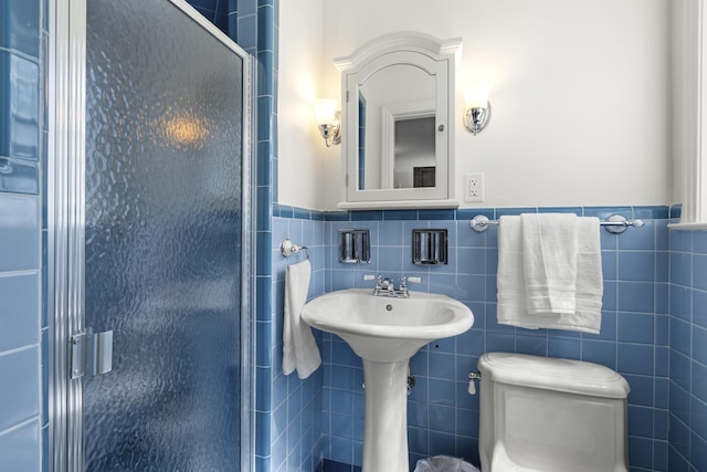bathroom featuring a shower stall, tile walls, a wainscoted wall, and toilet