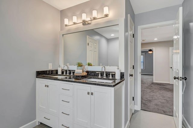 bathroom featuring a sink, baseboards, double vanity, and a ceiling fan
