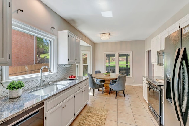 kitchen featuring light tile patterned floors, white cabinets, black appliances, decorative backsplash, and a sink