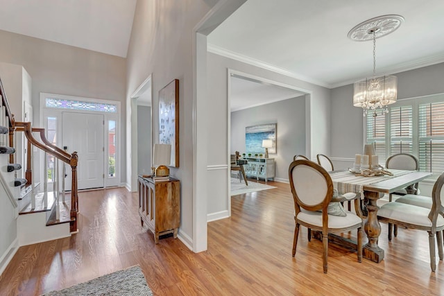interior space featuring a notable chandelier, light wood-type flooring, baseboards, crown molding, and stairs