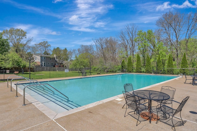 community pool with outdoor dining space, a patio area, and fence