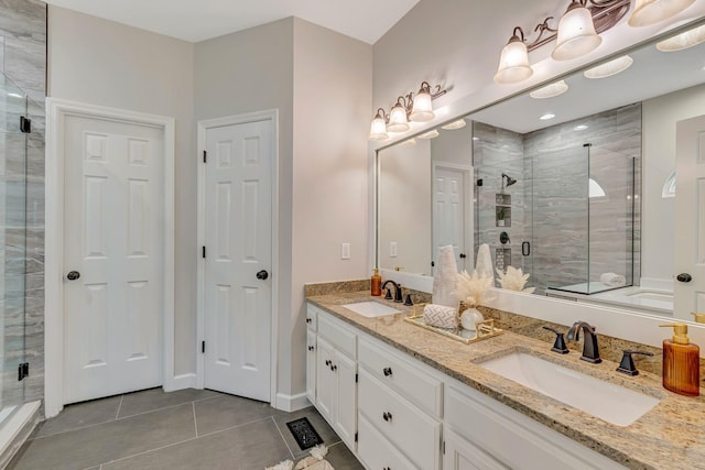 bathroom with a stall shower, double vanity, a sink, and tile patterned flooring