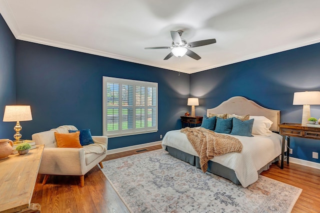 bedroom with baseboards, ornamental molding, a ceiling fan, and wood finished floors