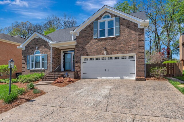 traditional-style house featuring an attached garage, driveway, fence, and brick siding