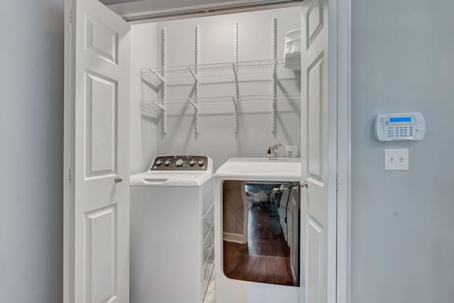 washroom with washer and dryer, laundry area, and wood finished floors