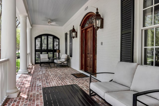 entrance to property with brick siding, a porch, and a ceiling fan