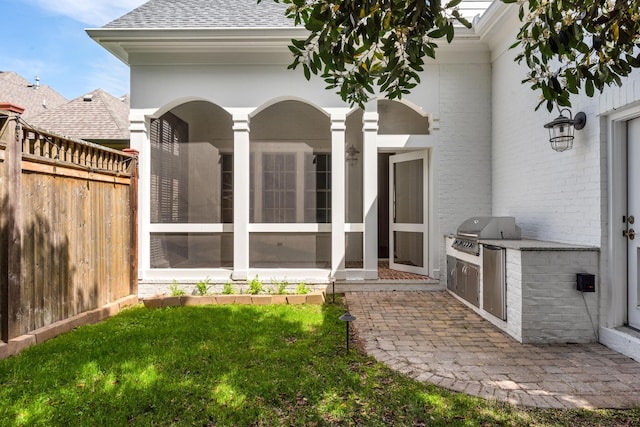back of property with an outdoor kitchen, a sunroom, a lawn, roof with shingles, and fence