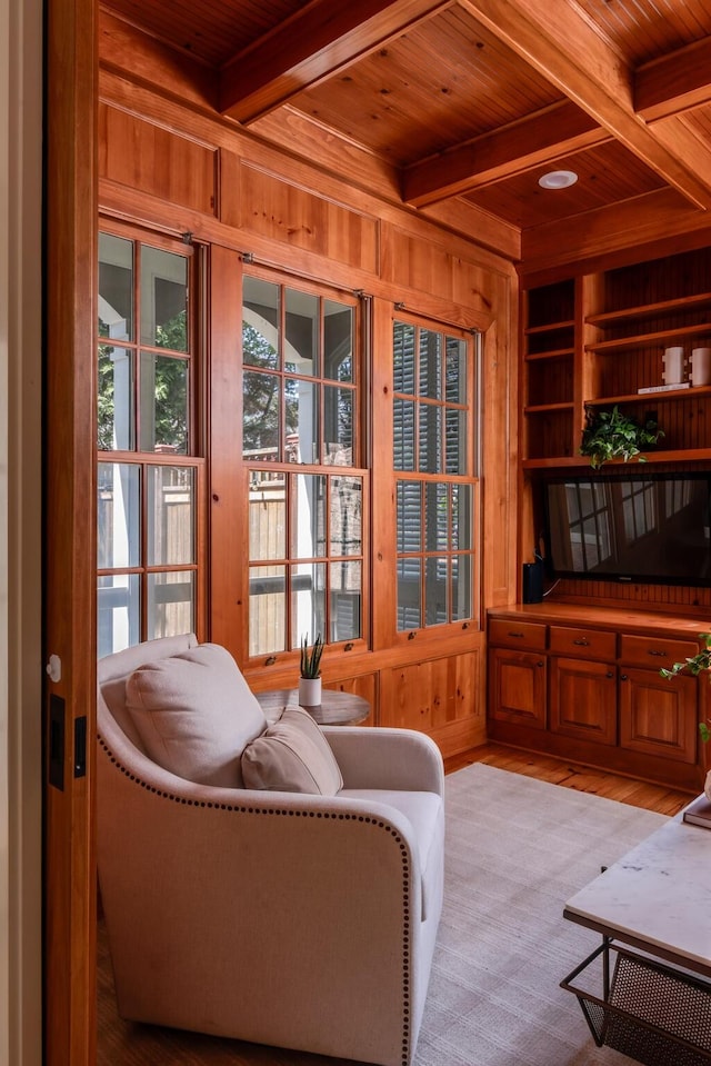 living area featuring wooden walls, wood ceiling, beam ceiling, and built in shelves