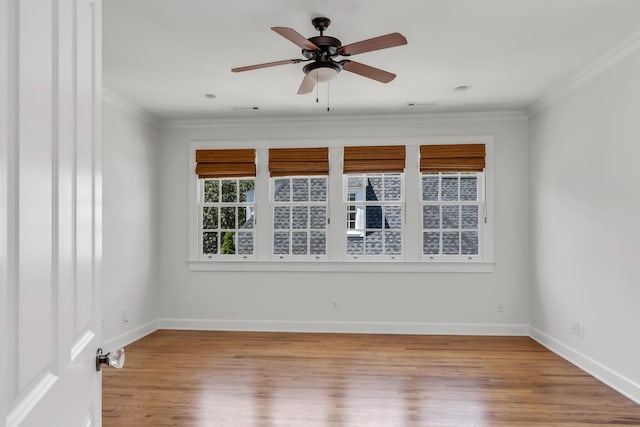 spare room with a ceiling fan, wood finished floors, baseboards, and ornamental molding