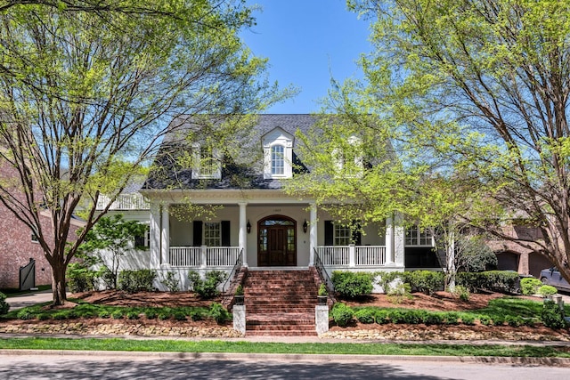 cape cod-style house featuring covered porch and stucco siding