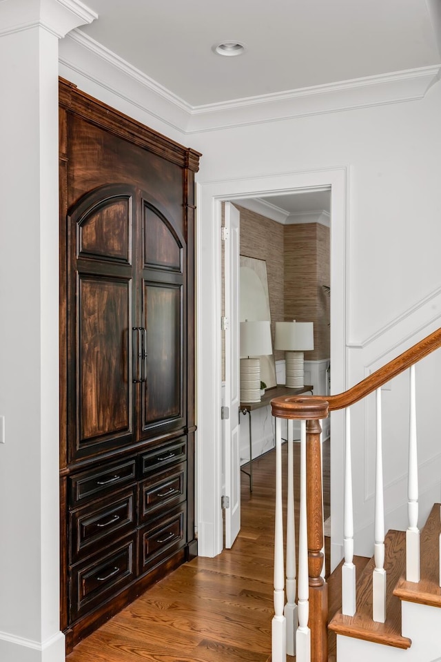 foyer entrance with crown molding, wood finished floors, and stairs