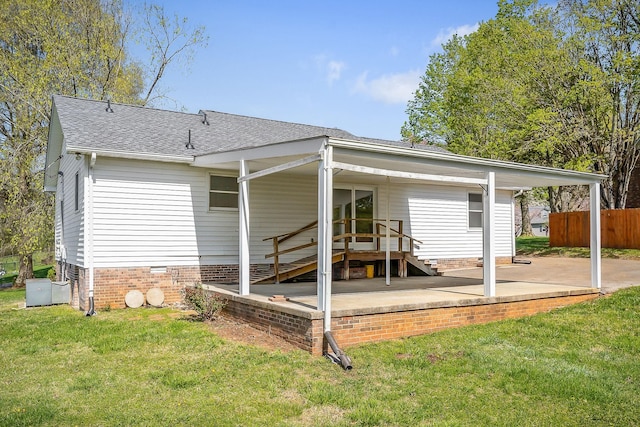 rear view of house featuring roof with shingles, crawl space, a patio area, a yard, and fence