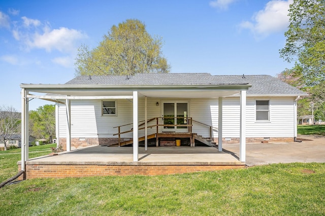 rear view of house with a patio, roof with shingles, crawl space, and a lawn