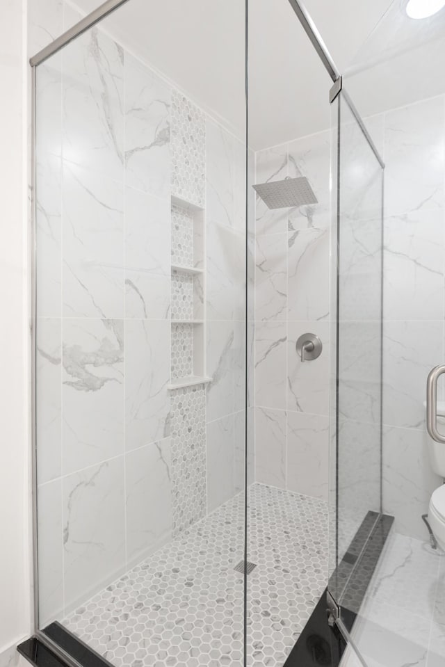 bathroom featuring toilet, a stall shower, and marble finish floor