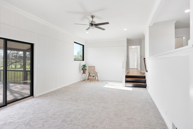 carpeted empty room with visible vents, baseboards, ornamental molding, a ceiling fan, and stairway