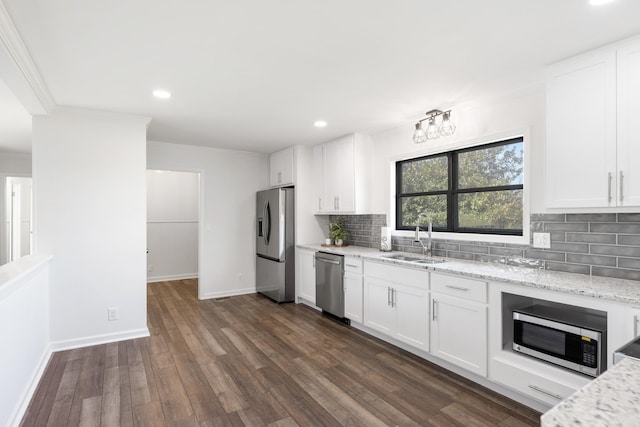 kitchen with white cabinets, a sink, stainless steel appliances, decorative backsplash, and light stone counters