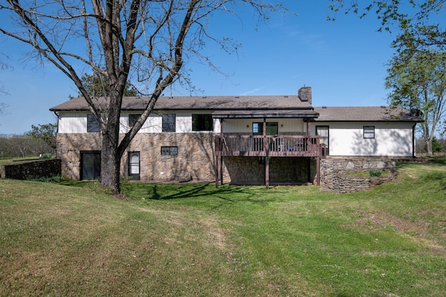 rear view of house featuring a yard, a wooden deck, stone siding, and a chimney