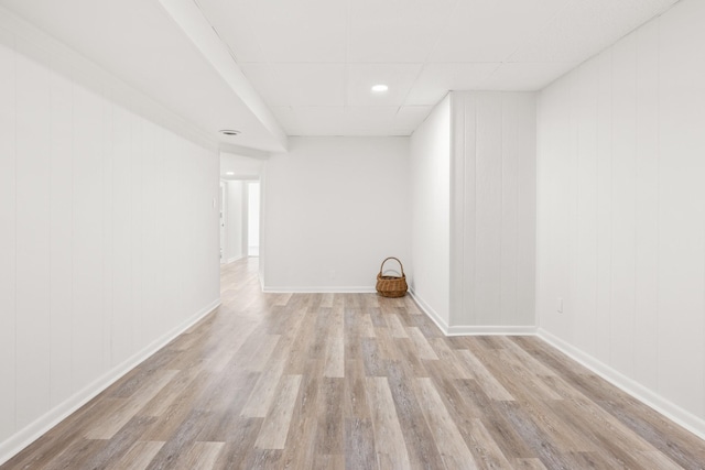 empty room with a paneled ceiling, wood finished floors, and baseboards
