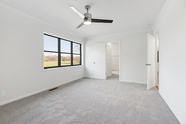 unfurnished bedroom with baseboards, crown molding, visible vents, ceiling fan, and light colored carpet