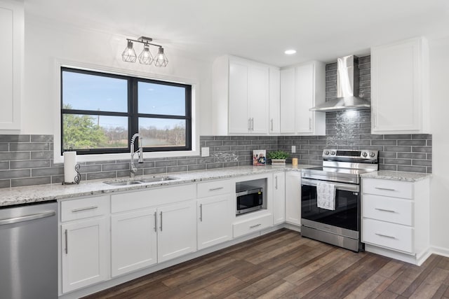 kitchen with wall chimney exhaust hood, white cabinets, appliances with stainless steel finishes, a sink, and dark wood-style floors