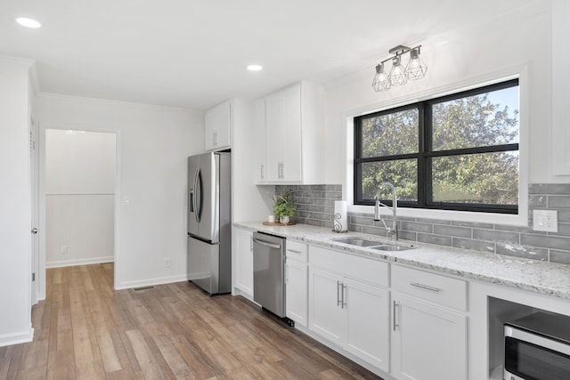kitchen featuring a sink, decorative backsplash, appliances with stainless steel finishes, and white cabinetry