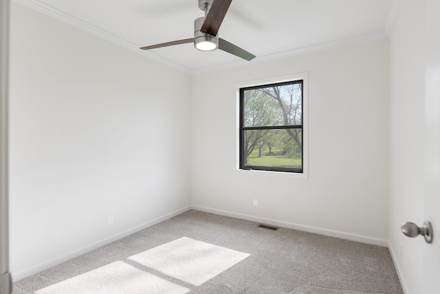 carpeted empty room featuring visible vents, baseboards, crown molding, and a ceiling fan